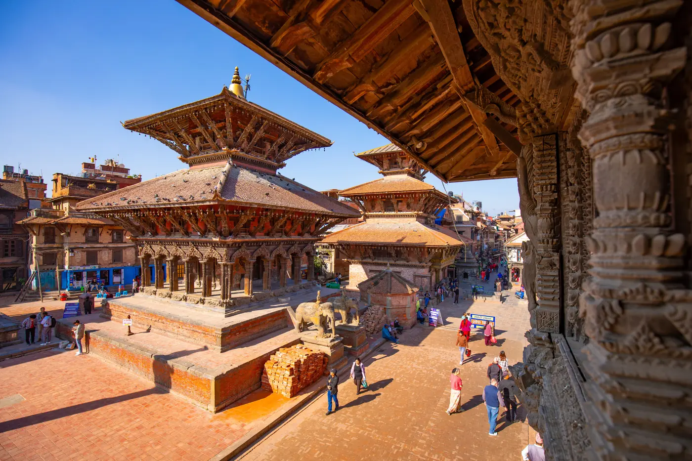 Kathmandu's Durbar Square at golden hour, showing temple architecture and some human presence for scale Specs